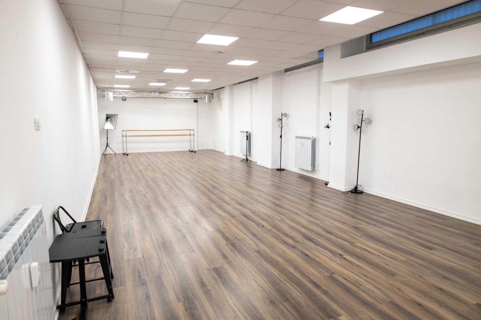 Sala ampia con pavimento in legno, pareti chiare e barre per la danza