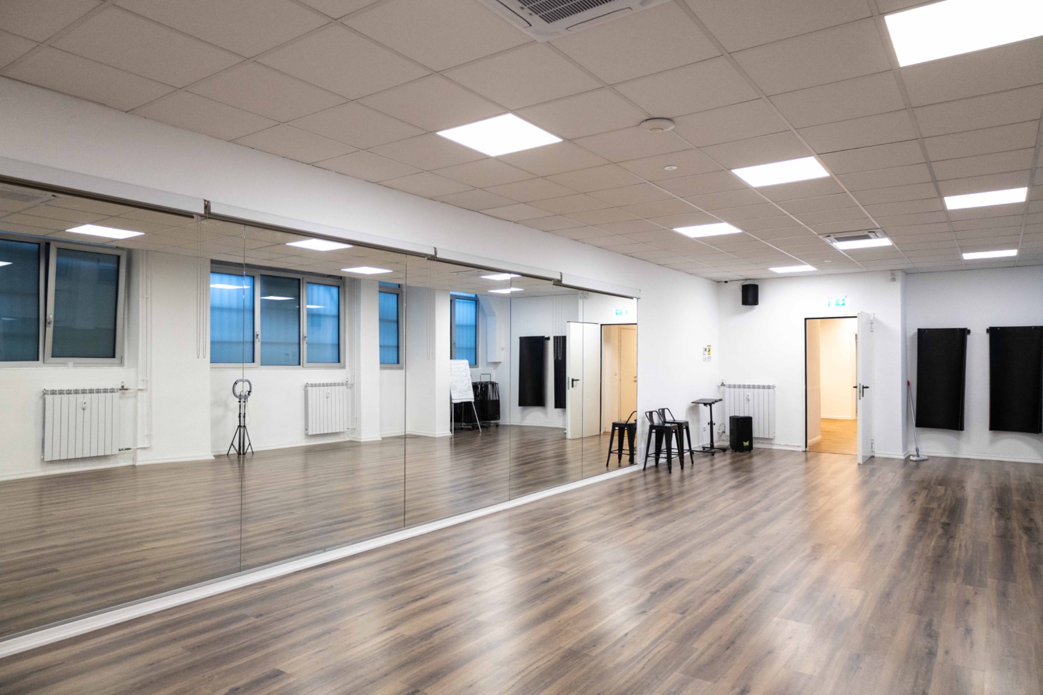 Sala luminosa con parete a specchio, pavimento in legno e finestre